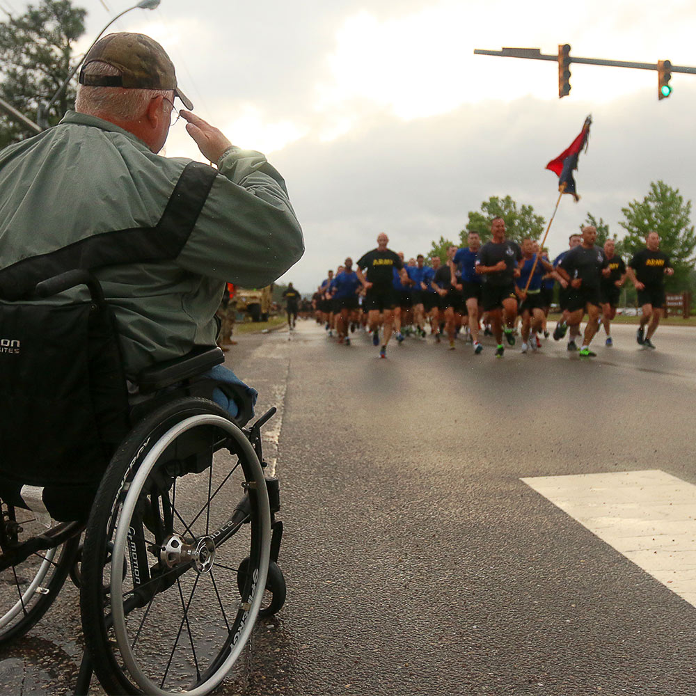 Veteran in wheelchair watching marathon runners.