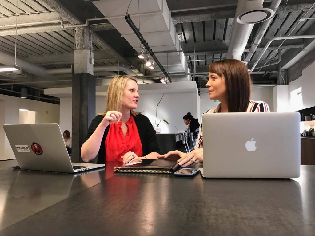 image of two women sitting at laptops talking