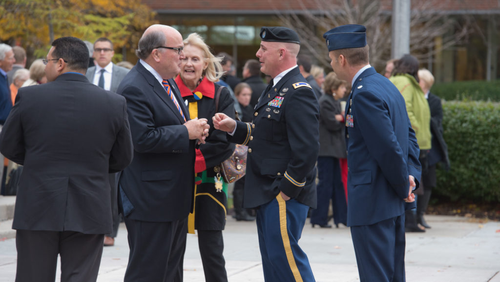 Two veterans communicating at the Syracuse University veterans day ceremony.