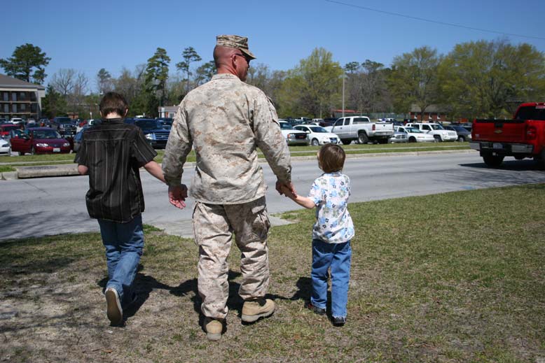 Shane Murray holding his children's hands and walking,. 