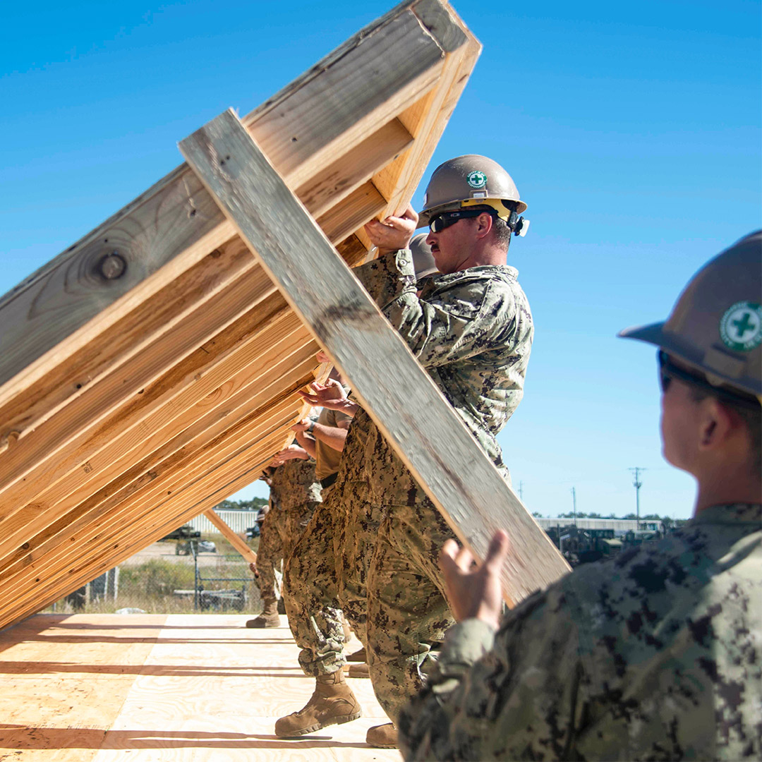 Soldiers lifting building houses and lifting wall structure.