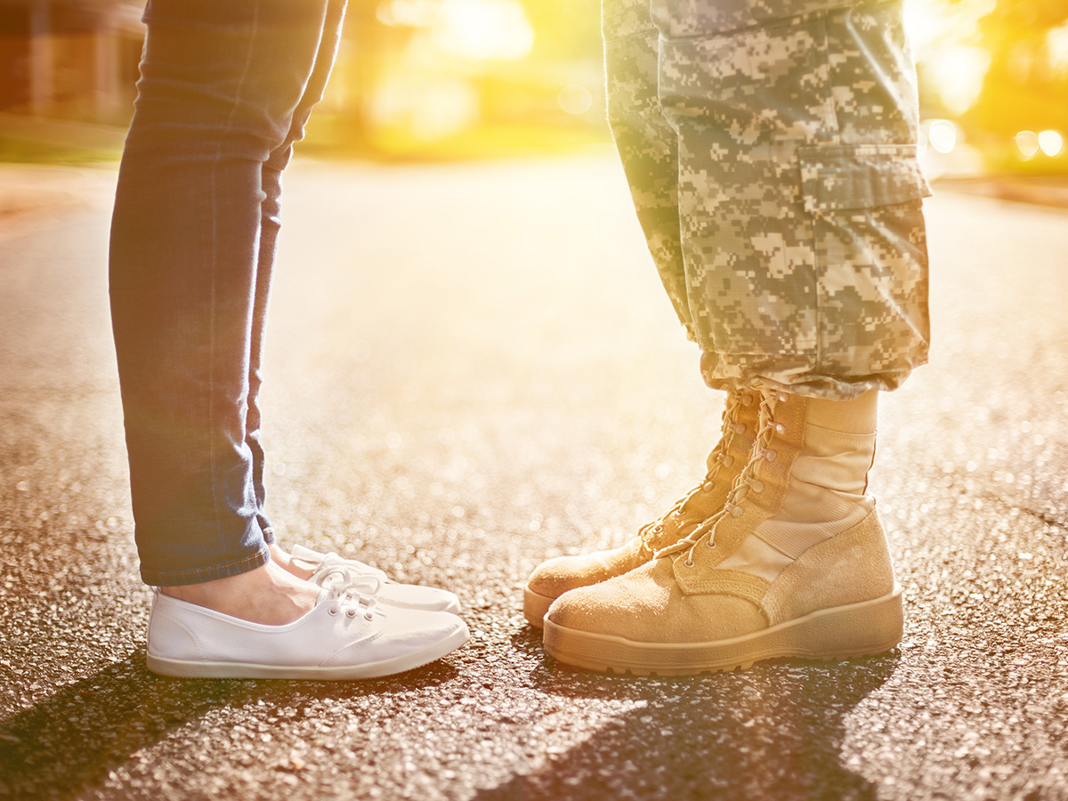 Uniformed man standing in front of woman - only show their legs. 