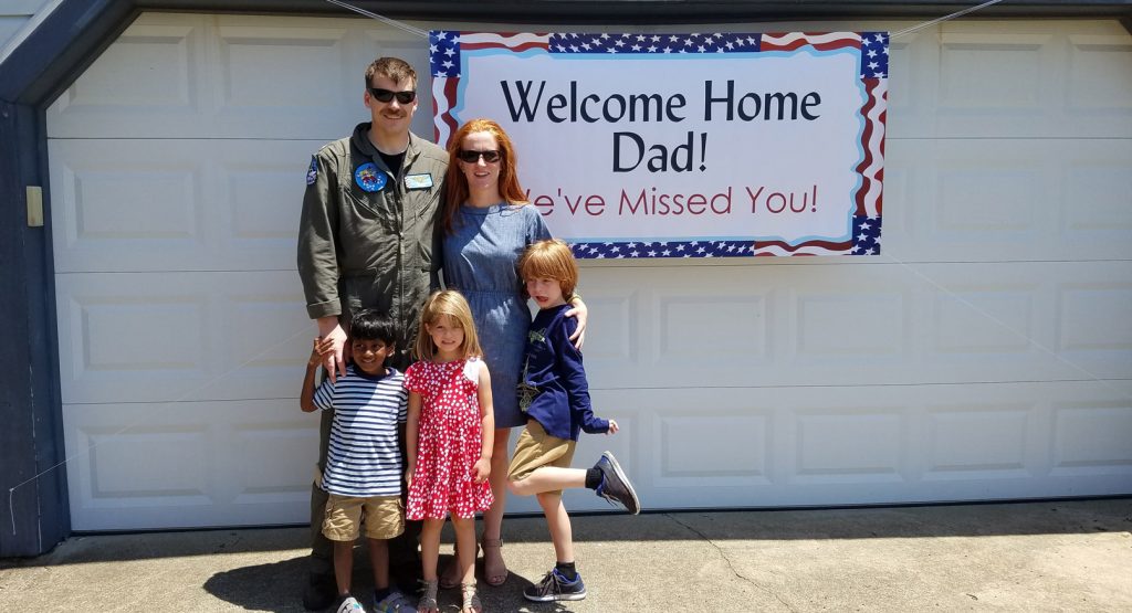 Kate and her family with a "welcome home dad" sign,.