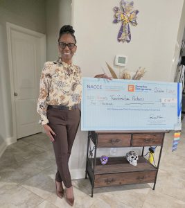 Pam Fleming standing in front of giant check she won. 